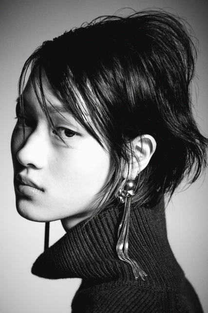 Portrait of a stylish woman in a turtleneck sweater and dangling earrings. Black and white fashion headshot with soft light.