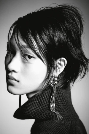 Portrait of a stylish woman in a turtleneck sweater and dangling earrings. Black and white fashion headshot with soft light.