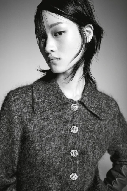 Monochrome portrait of an Asian woman with dark hair wearing a textured grey collared jacket with decorative crystal buttons in studio.
