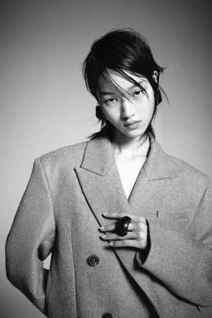 Model in oversized grey blazer wearing a statement ring against a neutral studio background
