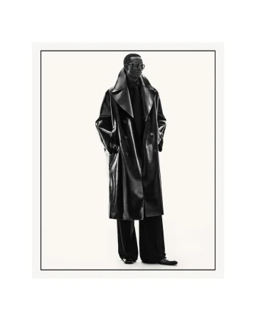 Black male model wearing an oversized black leather trench coat and dark sunglasses against a seamless white studio background.