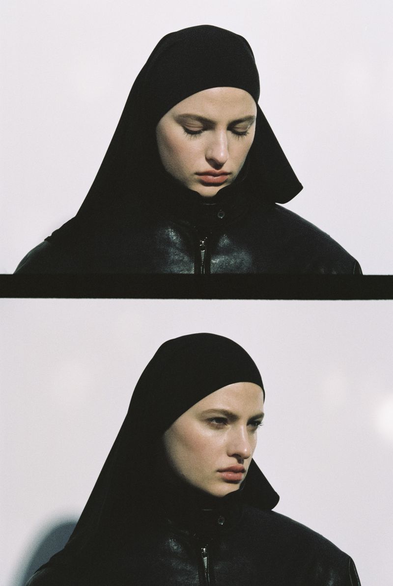Close-up of a young woman with fair skin and dark brown hair wearing a black hooded jacket against a white backdrop, duplicated.