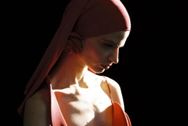 Model wearing a red headscarf and matching garment against a deep black background, captured by Vitali Gelwich.