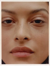 Close-up portrait focusing on a model's face with natural skin texture and minimal makeup for Mango.