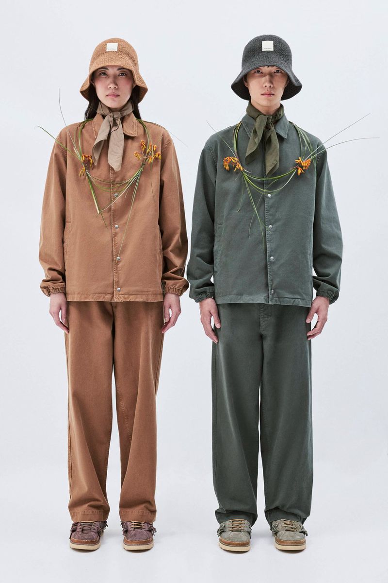 Two people stand side by side wearing matching casual outfits with bucket hats and flower details in a bright indoor photo studio setting.