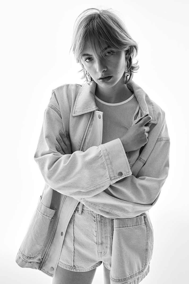 Model in denim jacket and shorts posing against a white seamless background for H&M Spring Summer 2024 campaign