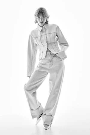 Model in denim jacket and wide-leg jeans posing against a plain white background
