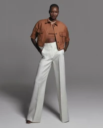 Model in brown utility jacket and white trousers standing against grey studio backdrop for Max Mara SS24