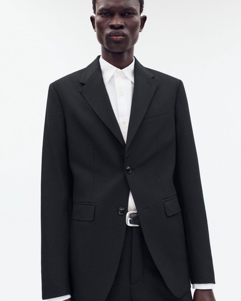 Model wearing a black blazer over a white shirt against a bright white background for Zara Origins Archetype