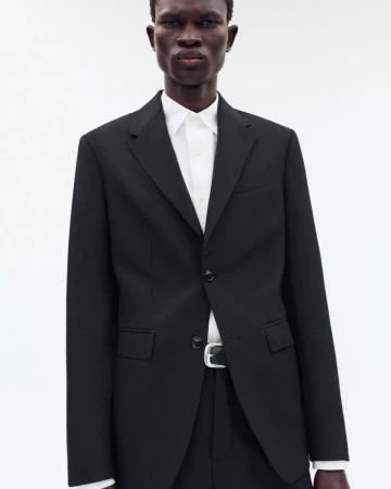 Model wearing a black blazer over a white shirt against a bright white background for Zara Origins Archetype