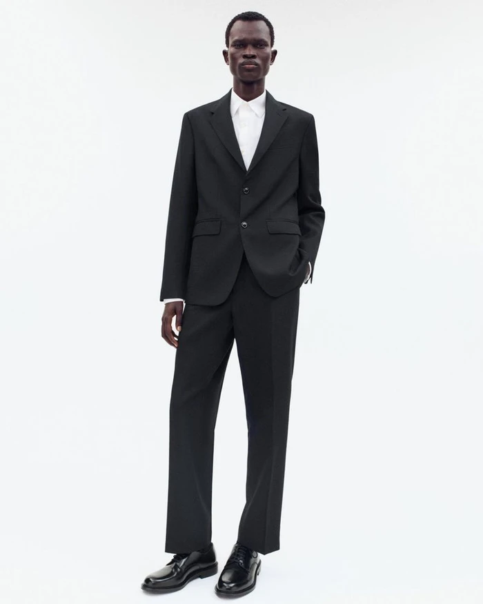 Black man wearing a black suit and white shirt standing against a white seamless background for Zara Origins