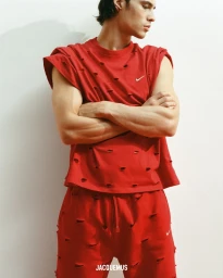 Model Louis Baines wearing a red distressed t-shirt and matching shorts against a plain white studio background.
