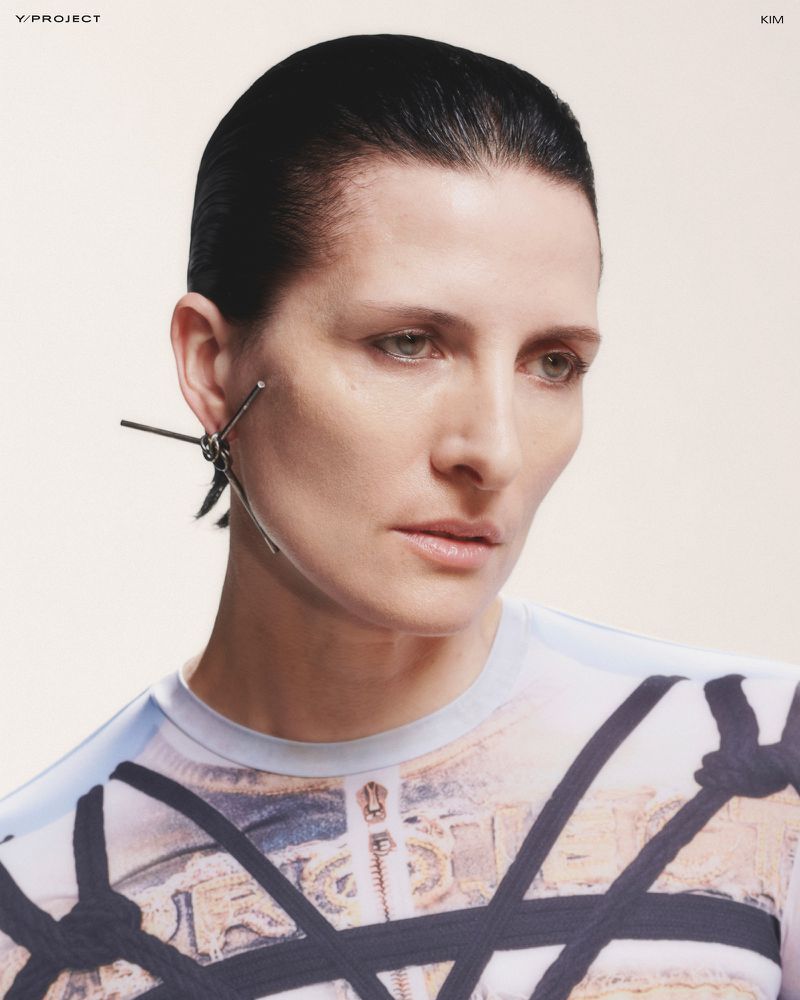 Close-up studio portrait of a stylish adult woman with dark hair and unique earrings, wearing a patterned shirt. Beauty and fashion.