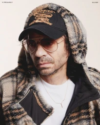 Portrait of Olivier Zahm wearing aviator sunglasses, a black baseball cap, and a fuzzy plaid hooded jacket for Y/Project F/W 24.