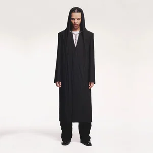 Model wearing a black hooded coat and silver necklace against a plain white studio background.