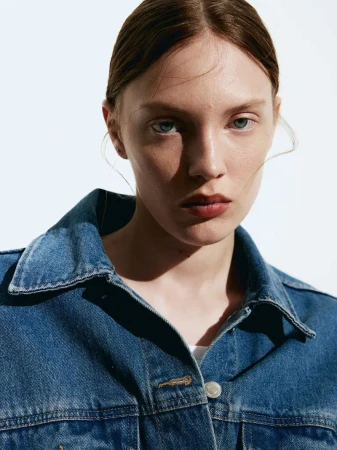 Close-up portrait of a woman wearing a blue denim jacket against a bright white background
