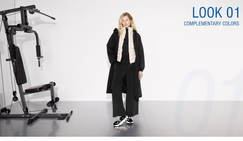 Fashion editorial shot in a photo studio featuring a blond female model wearing a black outfit next to exercise equipment.