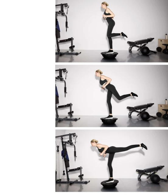Adult woman in fitness apparel performing balance exercise on a Bosu ball in a bright, minimalist indoor gym setting with workout equipment.