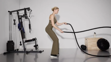 Model in olive green activewear working out with battle ropes in a studio setting by Ignazio Lozano for Oysho training.