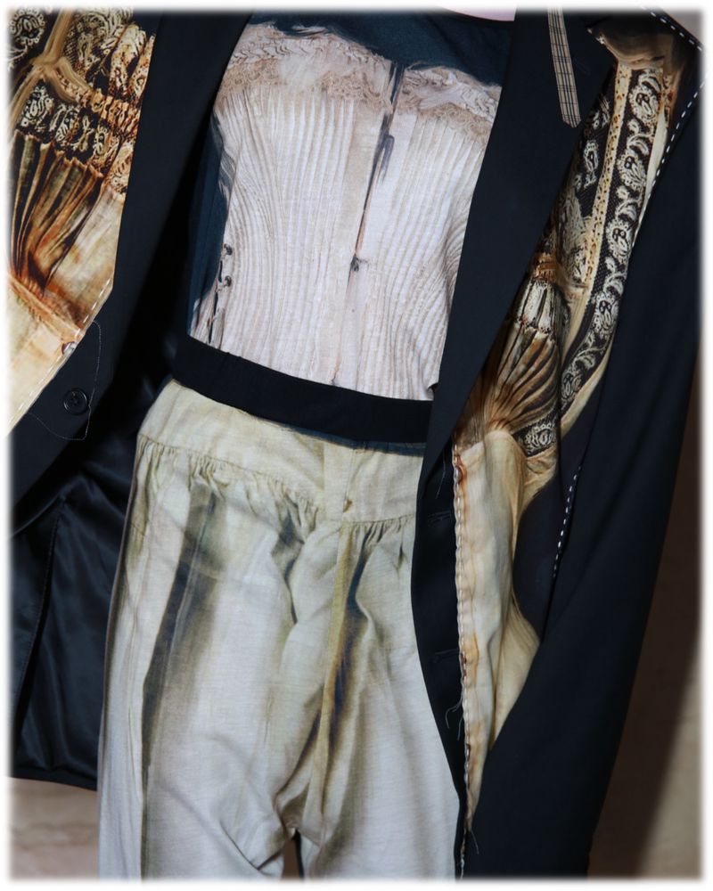Still life of a black blazer over a beige corset top and loose-fitting pants, creating a unique fashion ensemble in soft light.