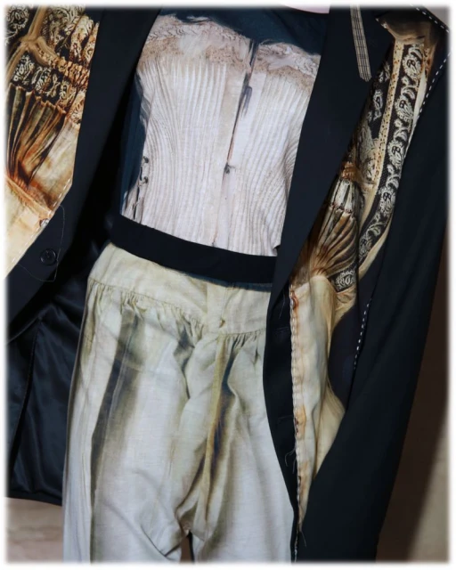 Still life of a black blazer over a beige corset top and loose-fitting pants, creating a unique fashion ensemble in soft light.