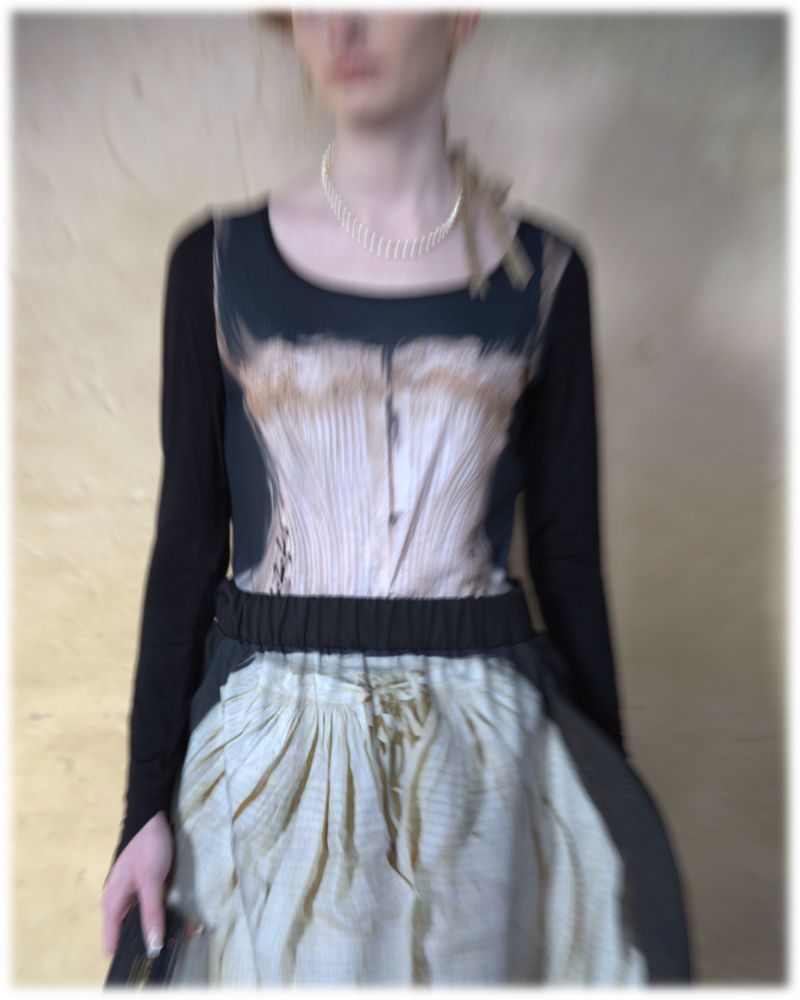 Female figure in long-sleeved shirt, corset-printed top, and skirt with lace-up detail against a textured beige backdrop.