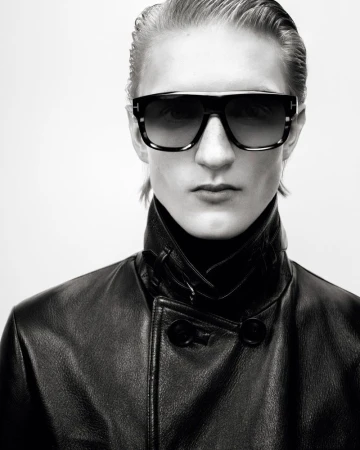 Black and white portrait of an adult wearing black leather jacket and sunglasses on a light background, fashion studio shot.