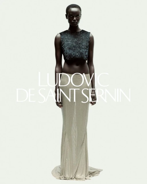 Elegant Black model poses in a green sequined crop top and a shimmering gold skirt in a fashion photo against a white backdrop.