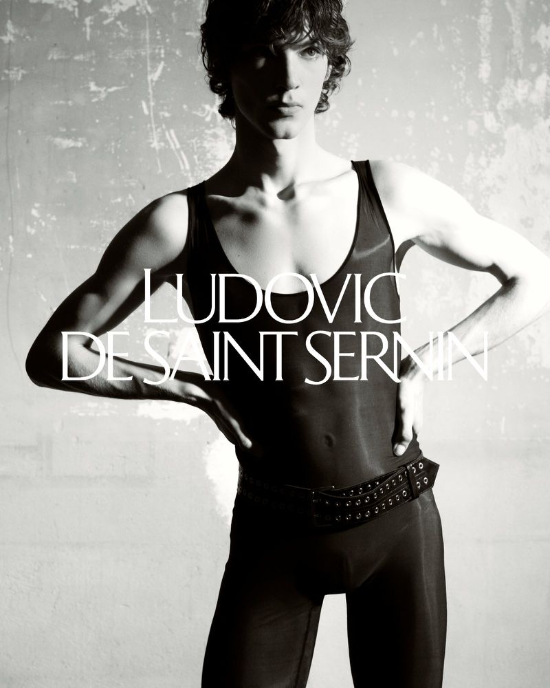 Model wearing a black tank top and studded belt against a distressed textured background for Ludovic de Saint Sernin lookbook