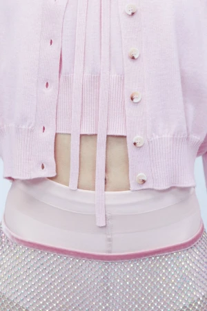 Close-up detail of a model wearing a light pink knit cardigan and embellished crystal mesh skirt for Sportmax.
