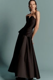Model Elise Crombez wearing a strapless black peplum gown against a teal backdrop.