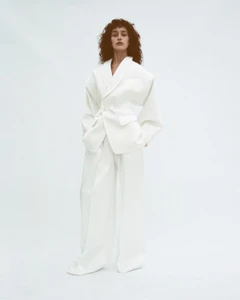 Model wearing a structured white blazer and matching trousers against a plain white background for Situationist.