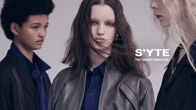 Fashion shot features three models in stylish jackets against a light backdrop, highlighting the S'yte Yohji Yamamoto collection.