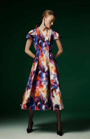 Model Roos Abels in a colourful patterned midi dress against a dark green studio backdrop for Jonathan Cohen FW24 lookbook.