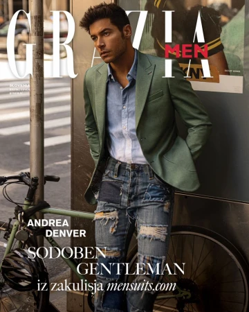 Model Andrea Denver leaning against a bus stop next to a bicycle wearing a green blazer and patchwork denim jeans