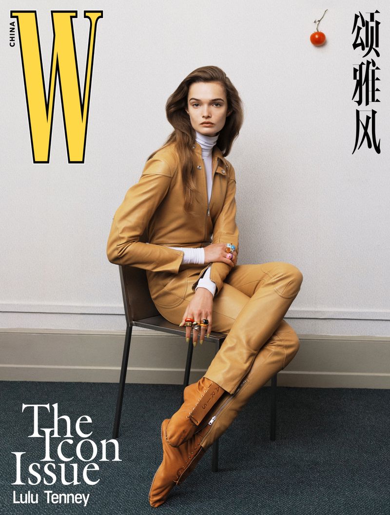 Magazine cover featuring a woman in a tan jumpsuit and boots, seated on a chair against a white wall, with magazine text overlay.