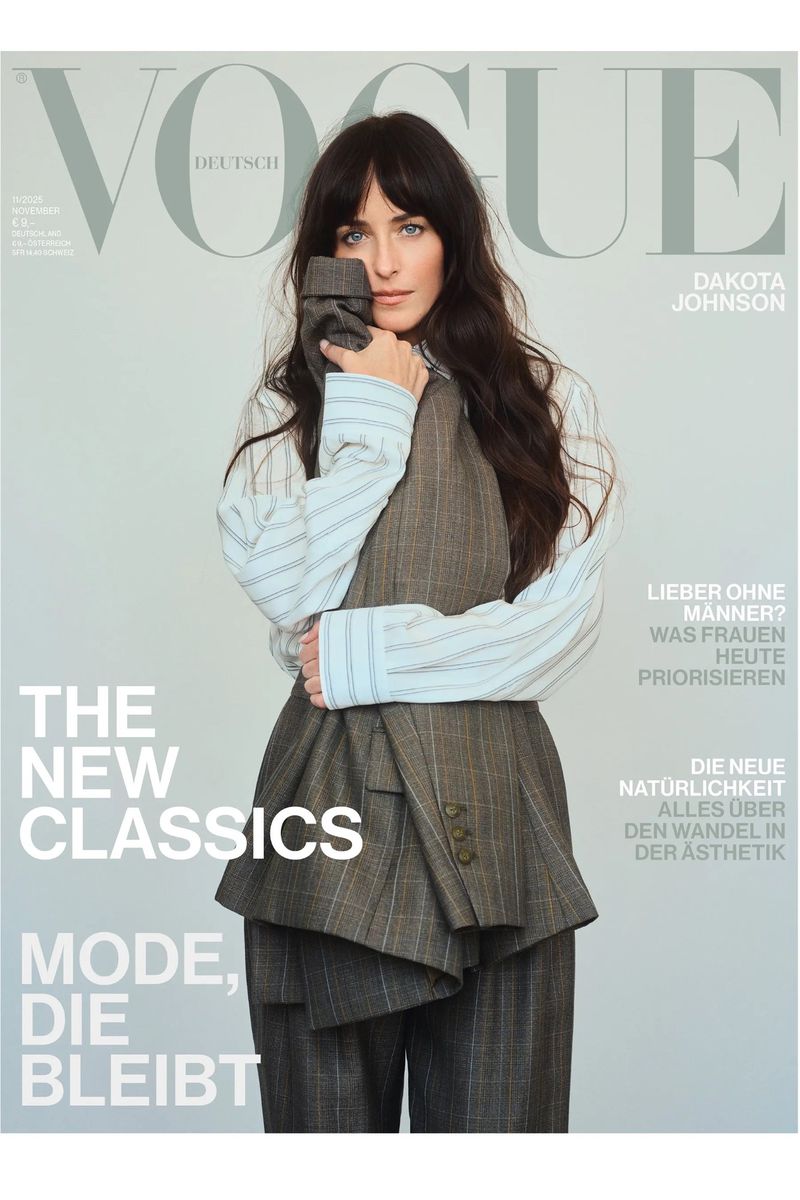 Vogue Deutsch cover featuring Dakota Johnson in a striped shirt and grey plaid suit, posing against a light grey backdrop.
