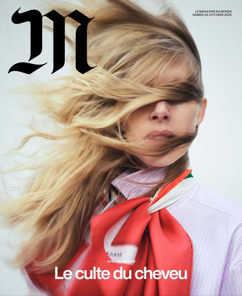 Magazine cover featuring a blond adult woman with hair obscuring her face, wearing a pink-striped shirt and colorful scarf.