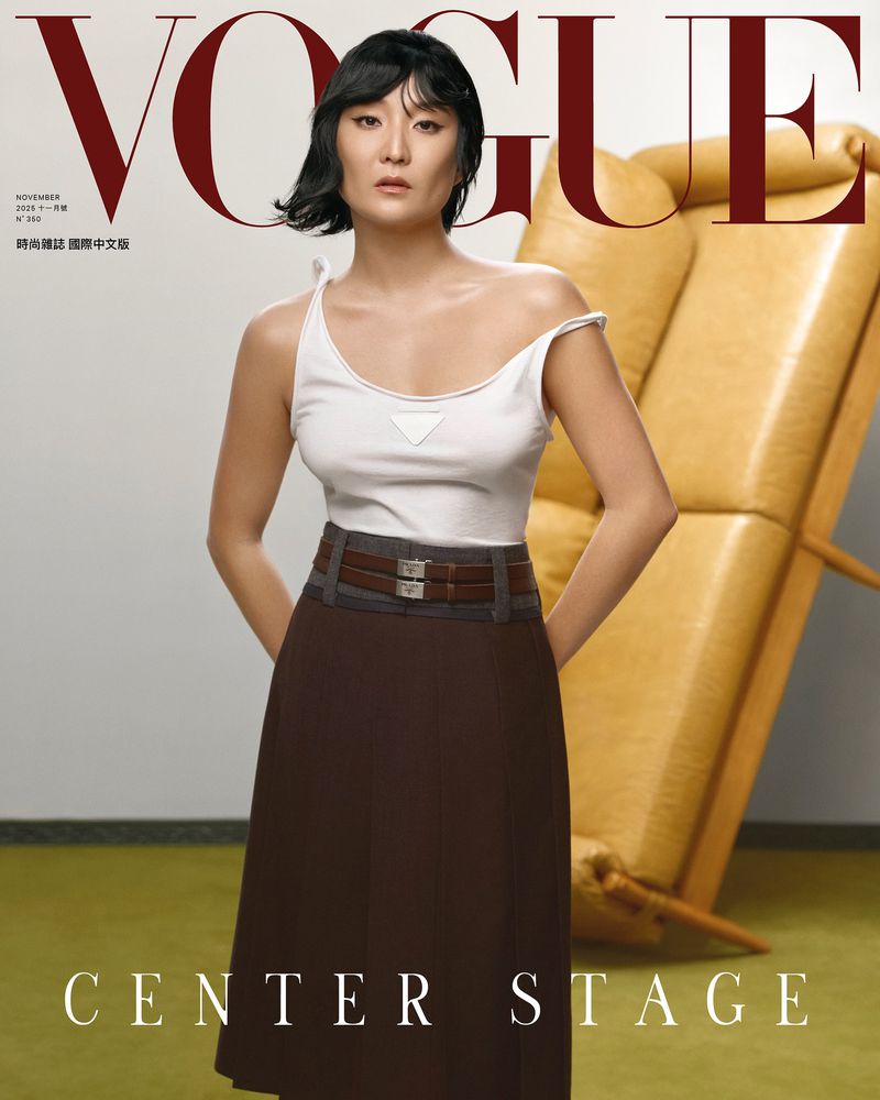 Vogue cover featuring an Asian woman in a white tank top and brown skirt posing in front of a yellow leather chair.