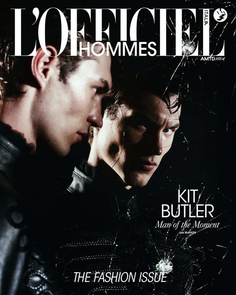 Magazine cover featuring two male fashion models in dark attire with dramatic lighting and a shattered glass overlay effect.