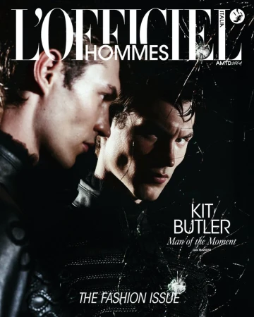 Magazine cover featuring two male fashion models in dark attire with dramatic lighting and a shattered glass overlay effect.
