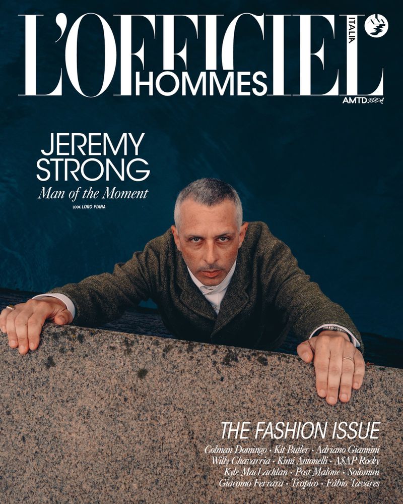 Fashion magazine cover featuring a man in a tweed jacket against a blurred blue background, with text overlay and neutral color palette.