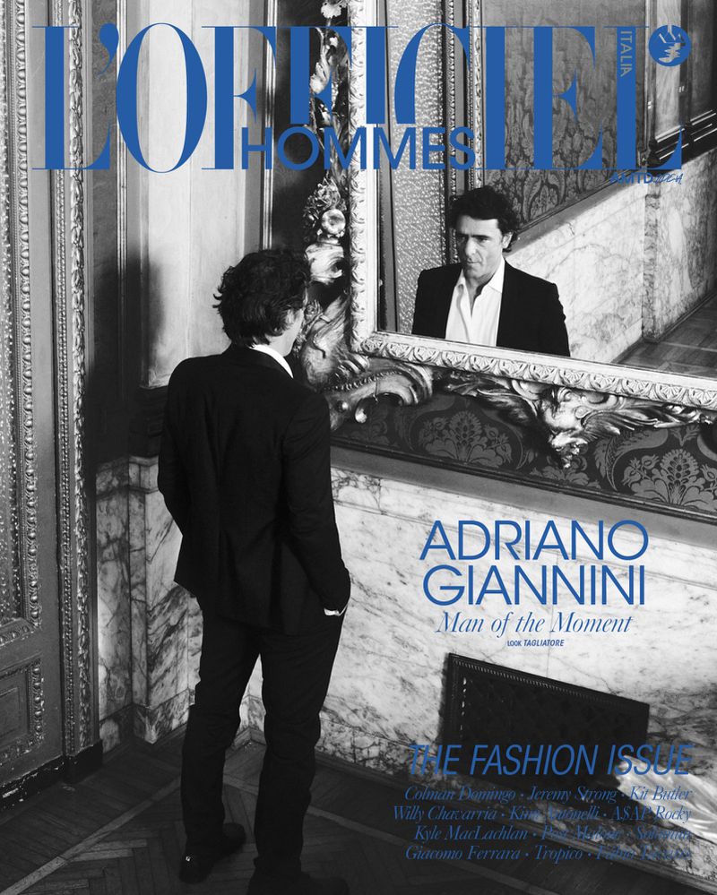 Black and white fashion cover featuring a man in a suit looking at his reflection in an ornate mirror with magazine text overlay.