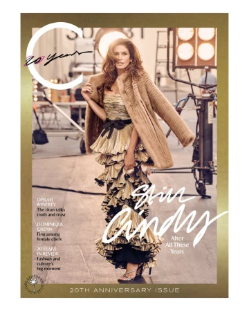 Magazine cover featuring a woman in a gold dress and fur coat, posing in a studio with stage lights and equipment in the background.