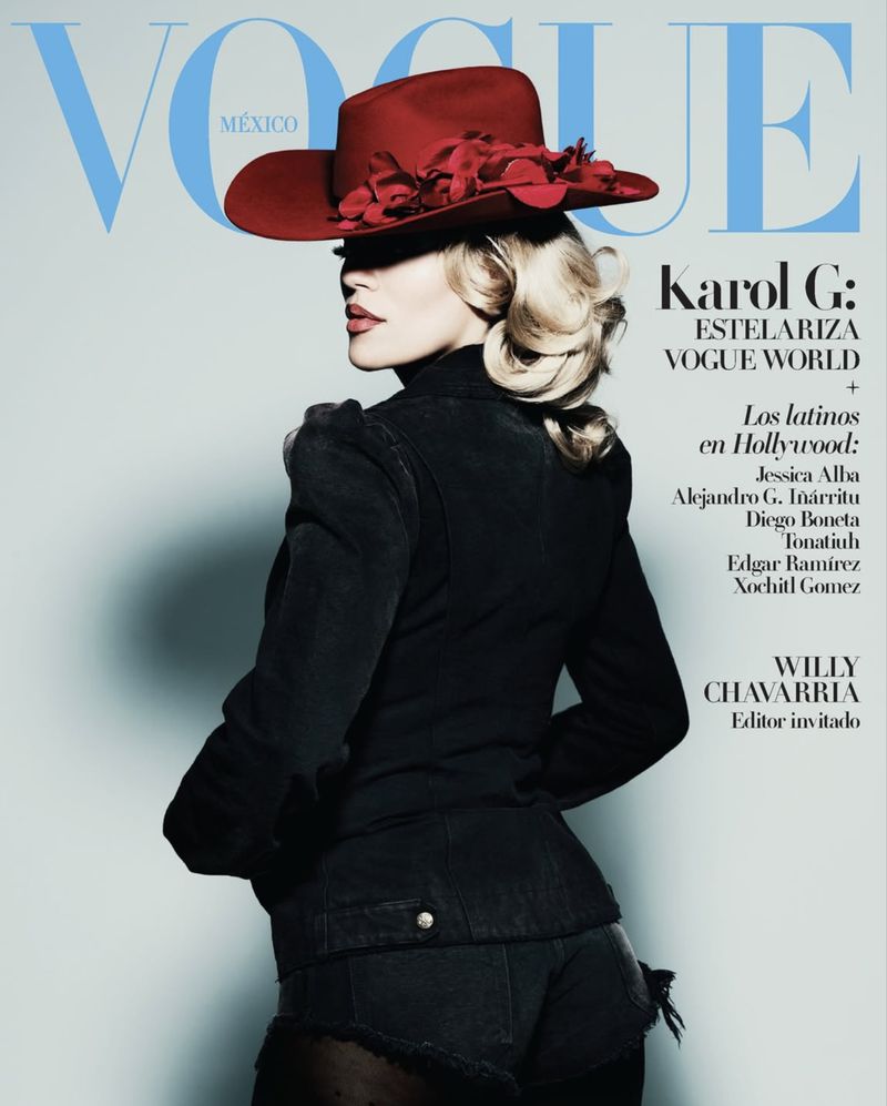 Vogue Mexico cover featuring Karol G wearing a red hat and dark jacket, posing against a light background with magazine title text overlay.