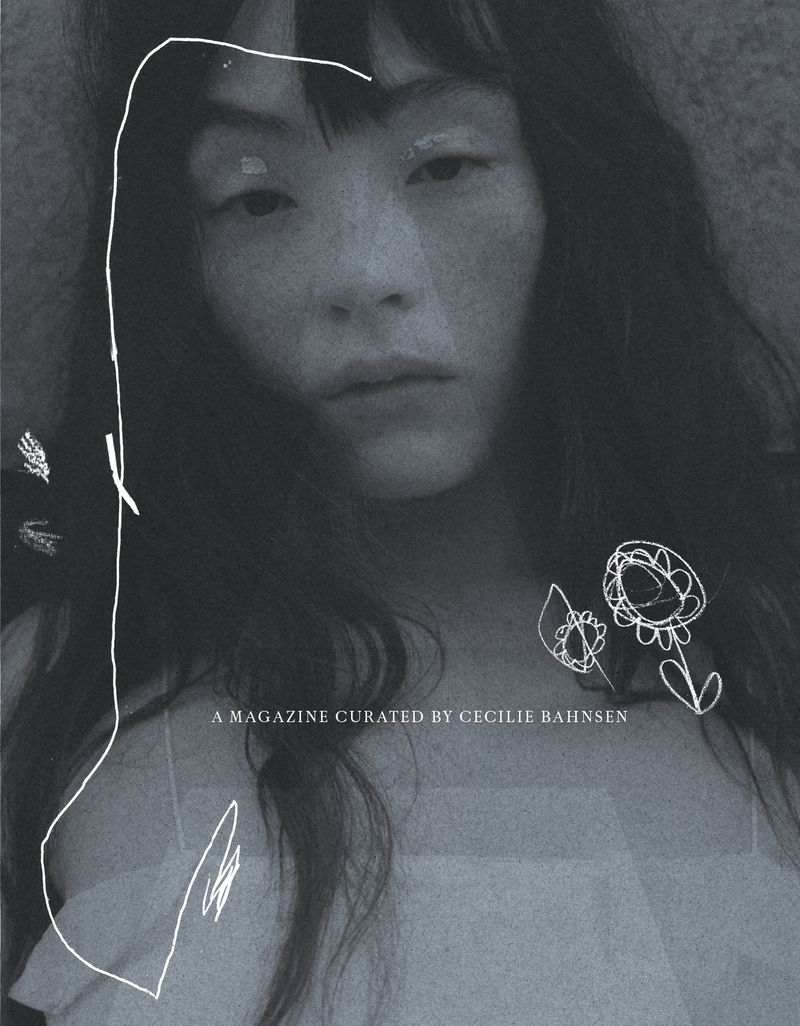 Black-and-white portrait of an East Asian woman with long dark hair and light makeup against a neutral background.