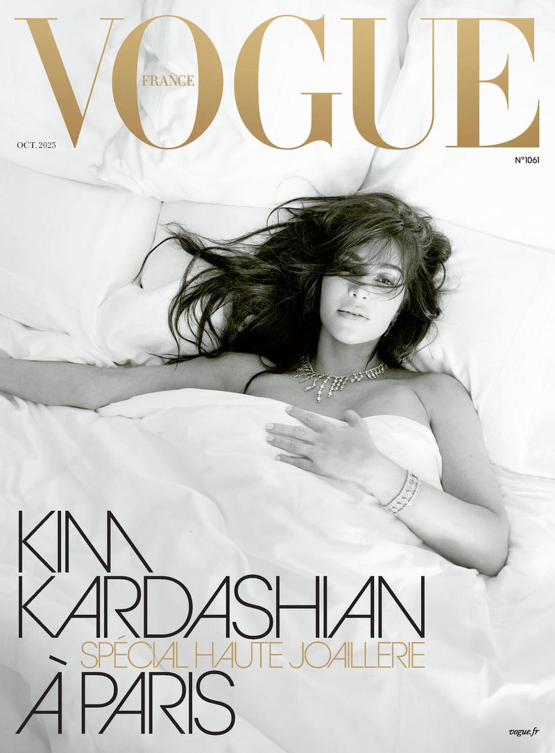 Vogue France cover featuring Kim Kardashian lying in bed with white sheets and pillow, wearing jewelry, shot in black and white.