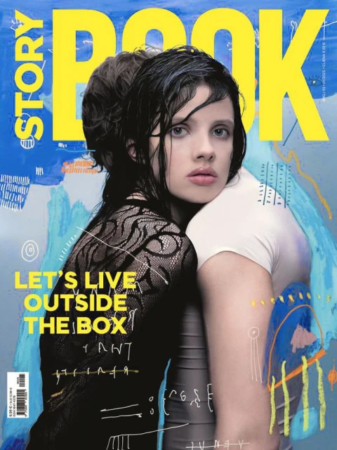 Magazine cover featuring two women, one in black lace and the other in white, against a backdrop of blue and yellow abstract art.