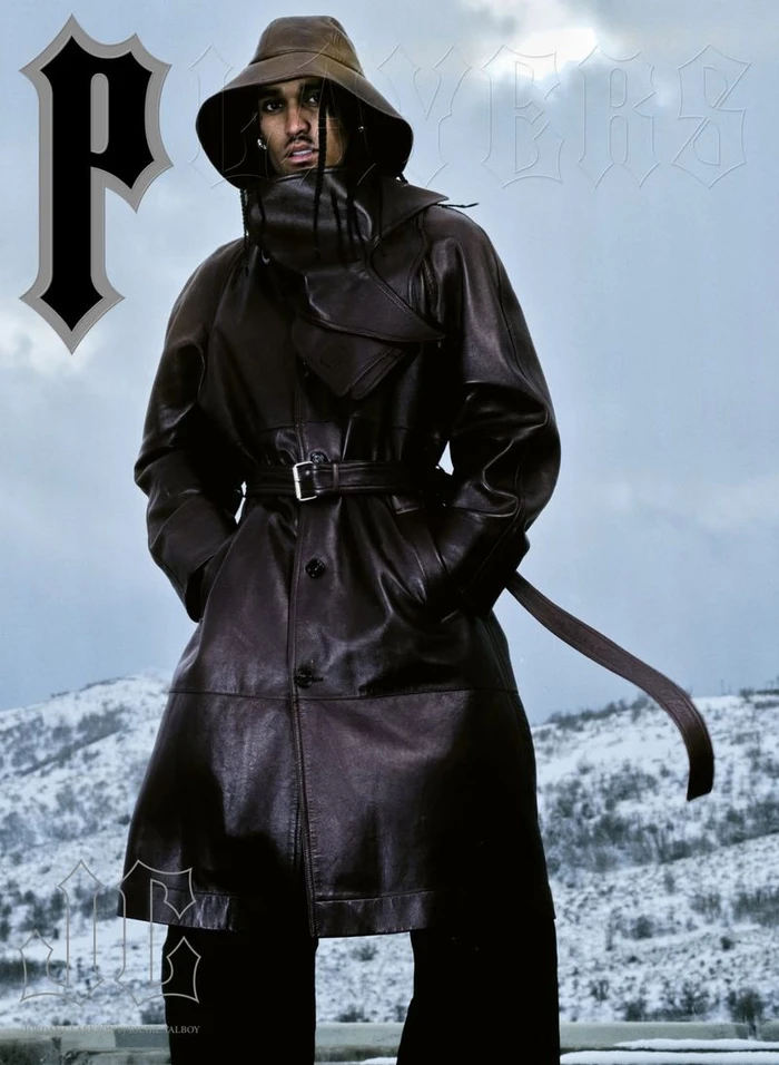 Man wearing a dark leather coat and matching bucket hat standing outdoors against a snowy landscape for Players
