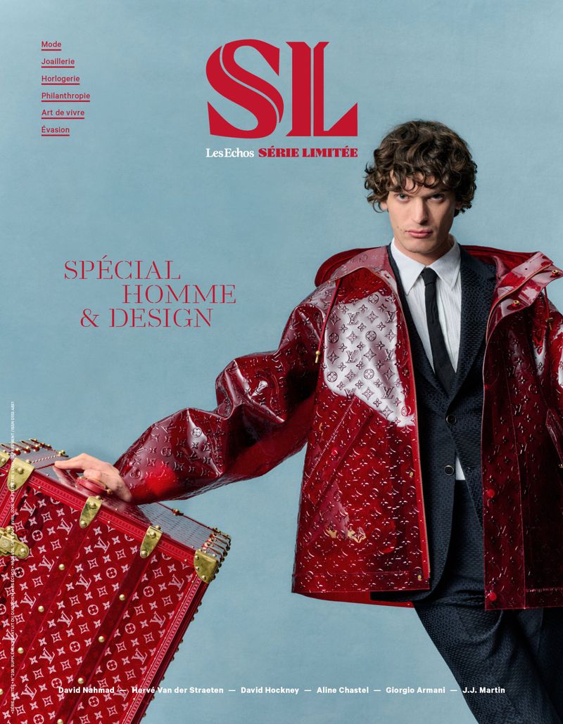 Magazine cover features a male model in a red, patterned jacket with a trunk, set against a light blue backdrop with text overlays.